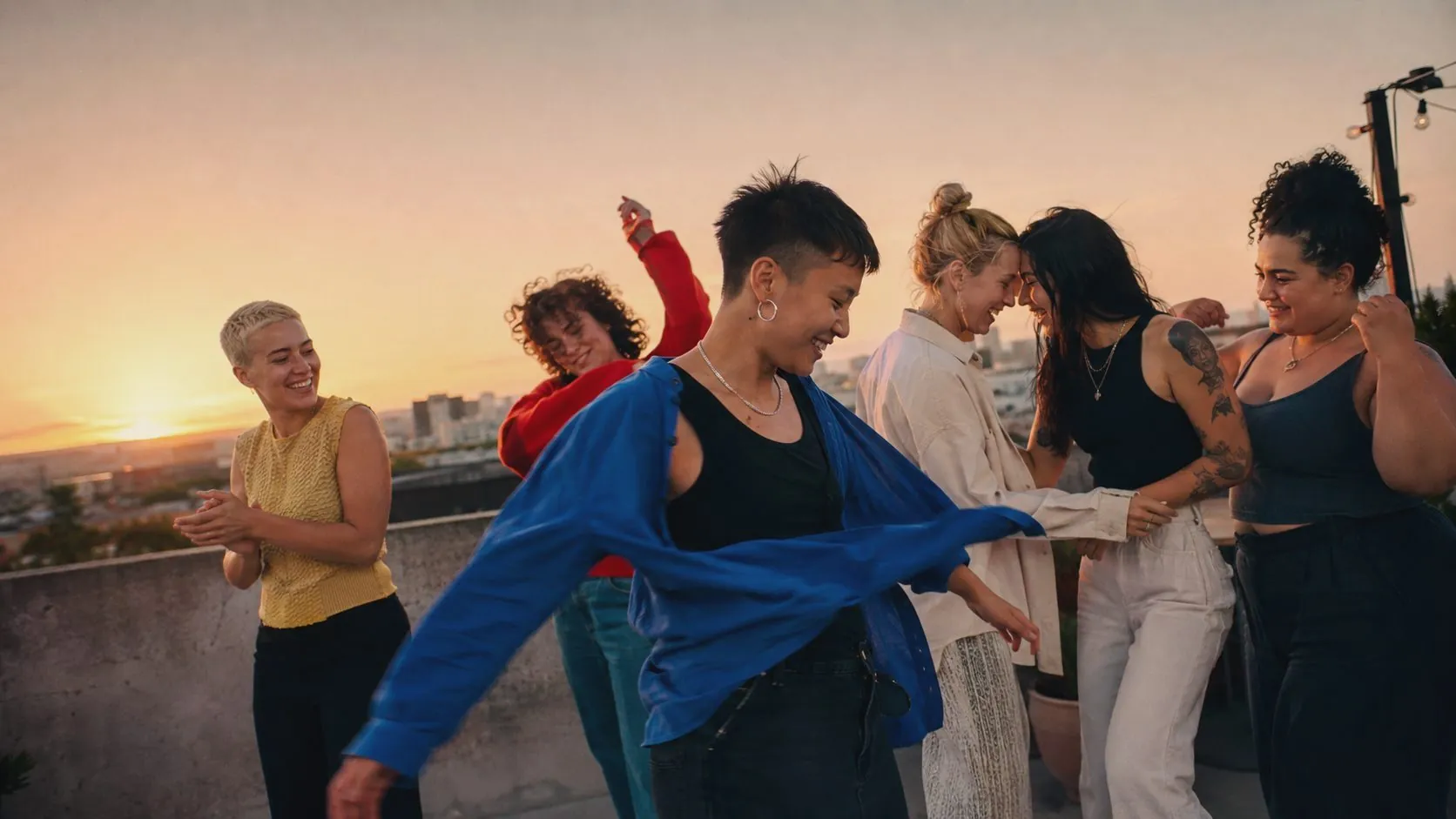 Queer friends laughing and dancing together at golden hour